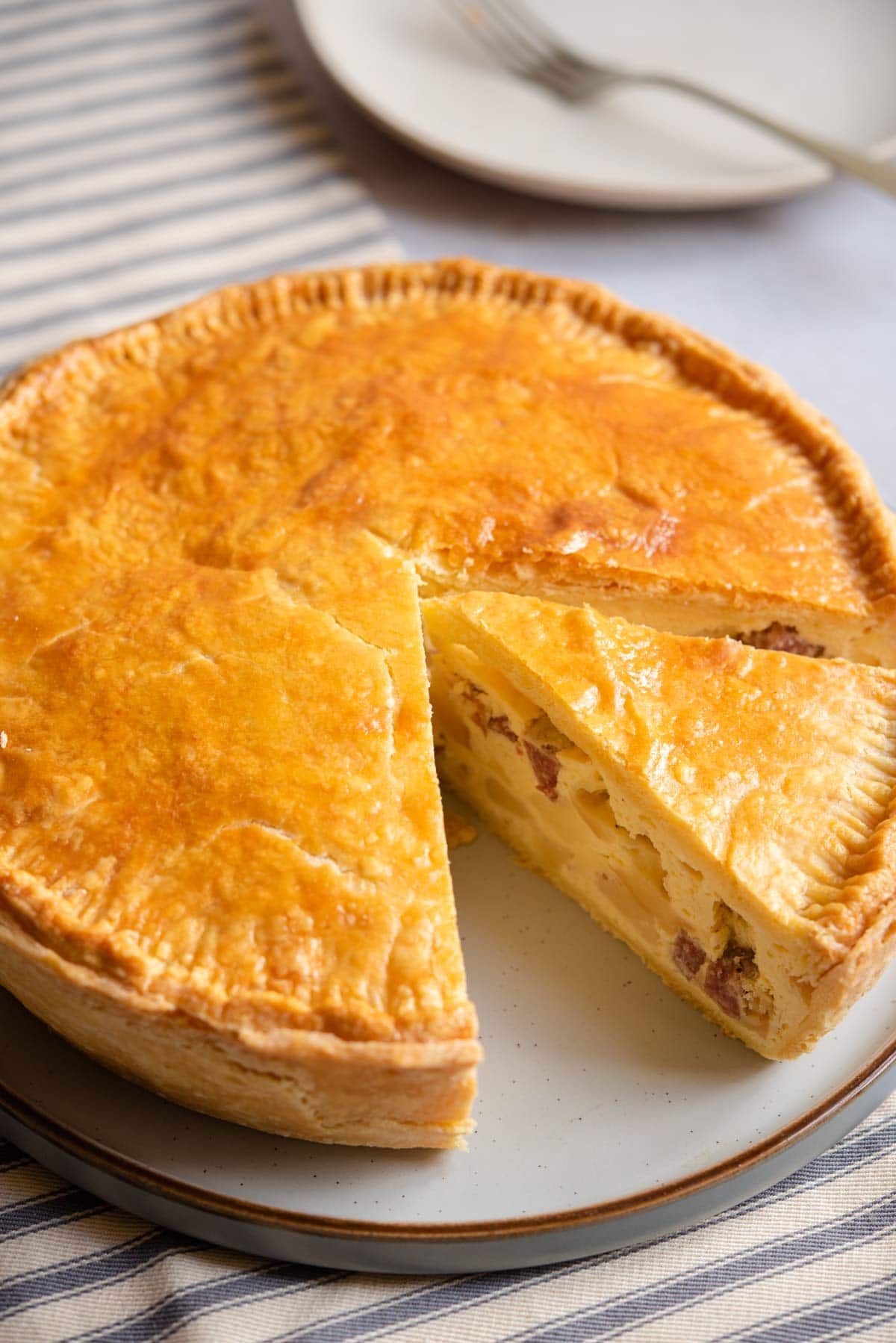 Pizza Rustica on a serving plate with a slice cut