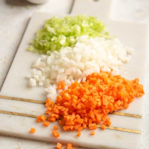 Finely chopped carrot, celery and onion on a chopping board