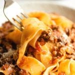 A close up of lamb ragu and pappardelle pasta on a fork