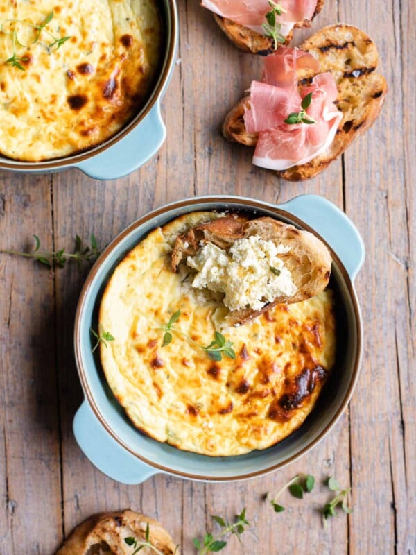 An overhead shot of baked ricotta in a blue dish with toasted bread at the side