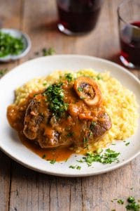 Osso Bucco on a plate of saffron risotto and topped with gremolata