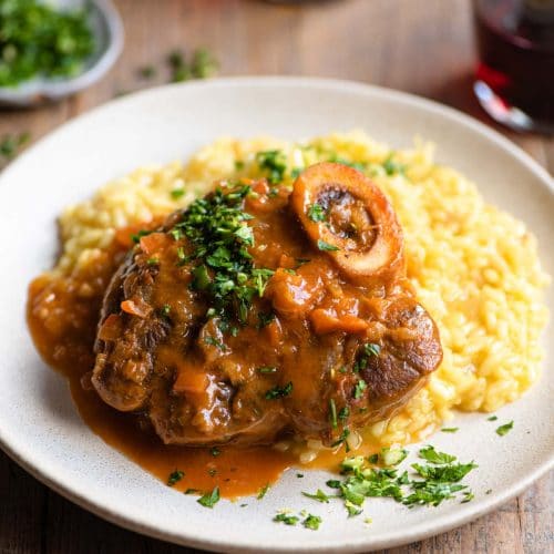 Osso Bucco on a plate of saffron risotto and topped with gremolata