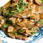 A close up of veal marsala on a blue servings plate