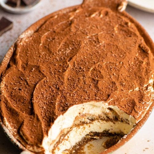 An oval dish of Tiramisu with a scoop out