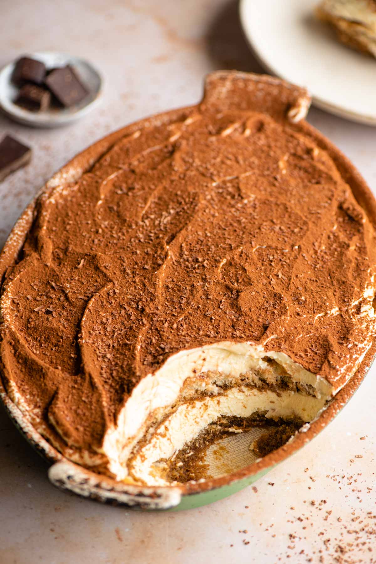 An oval dish of Tiramisu with a scoop out