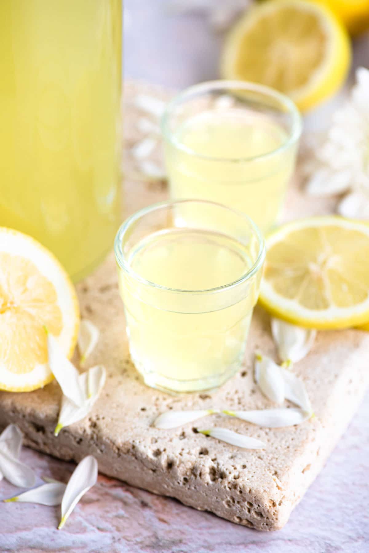 Two shot glasses filled with limoncello with slices of lemon at the side