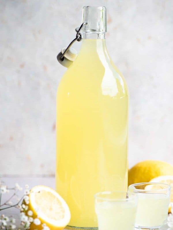 A bottle of homemade Limoncello with two shots glasses beside it