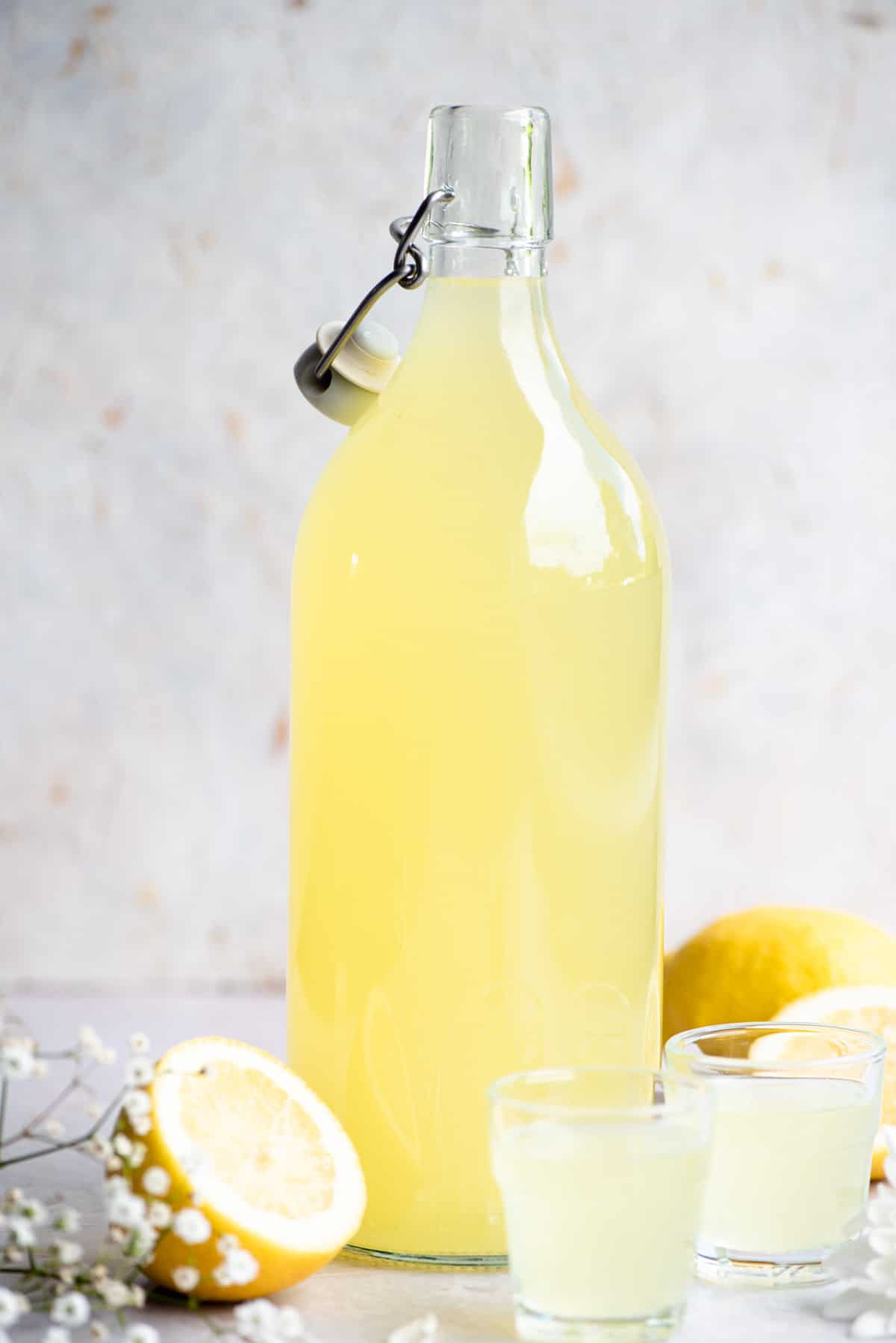 A bottle of homemade limoncello with two shots glasses at the side