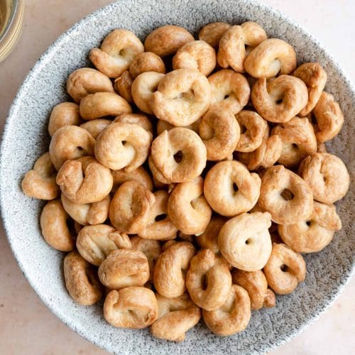 An overhead shot of Taralli in a bowl with glasses of wine at the side