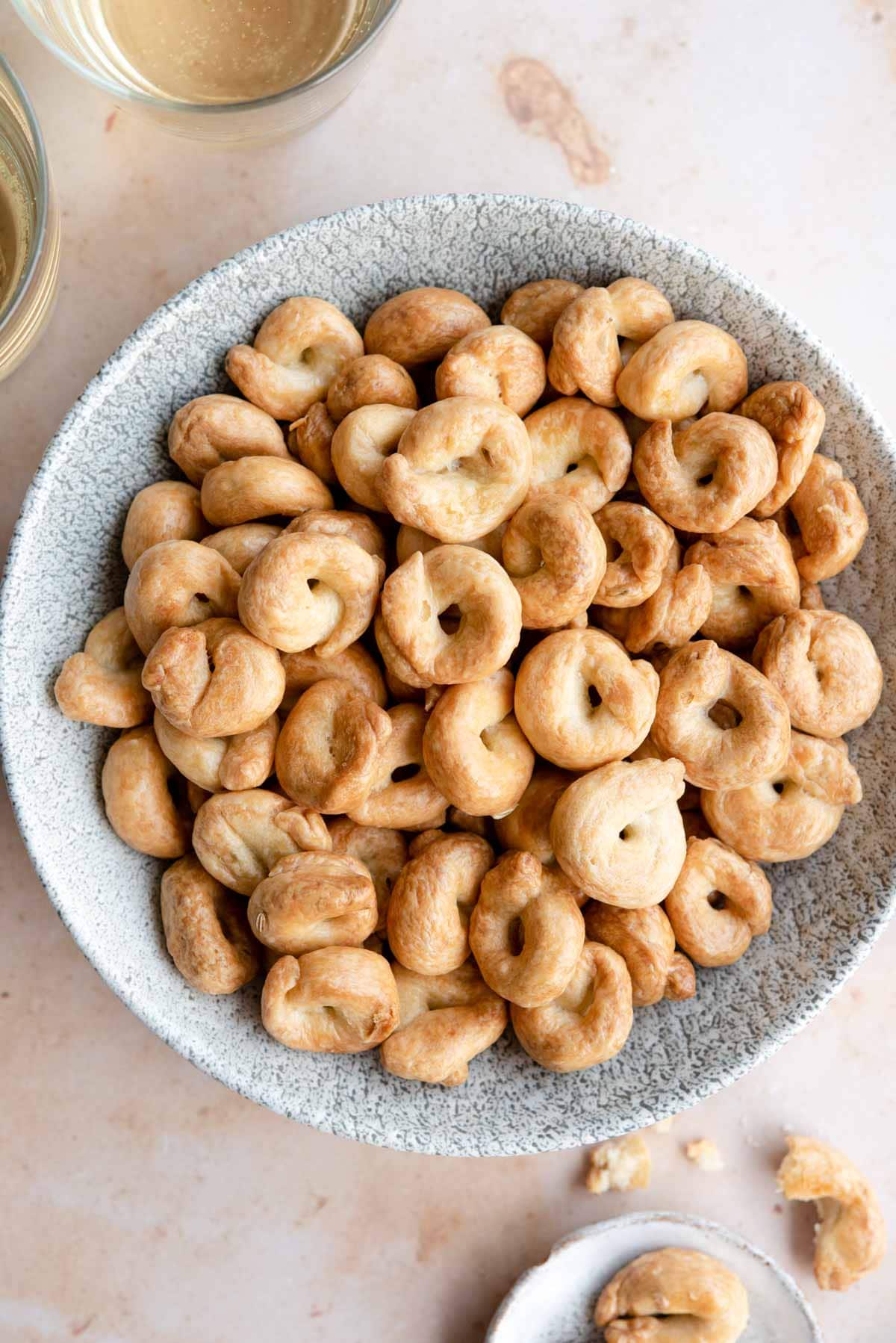 An overhead shot of Taralli in a bowl with glasses of wine at the side