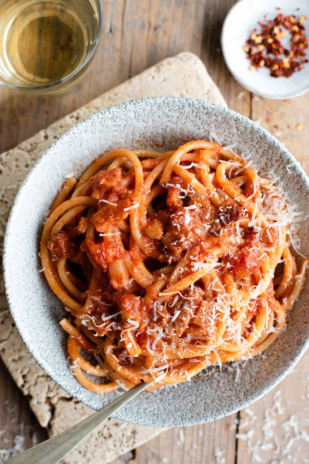 A close up of bucatini pasta with amatriciana sauce in a bowl