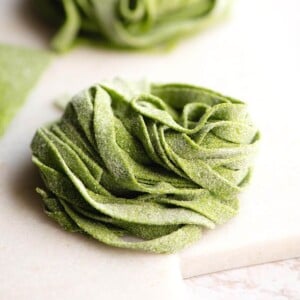 A close up of spinach pasta tagliatelle on a marble cutting board