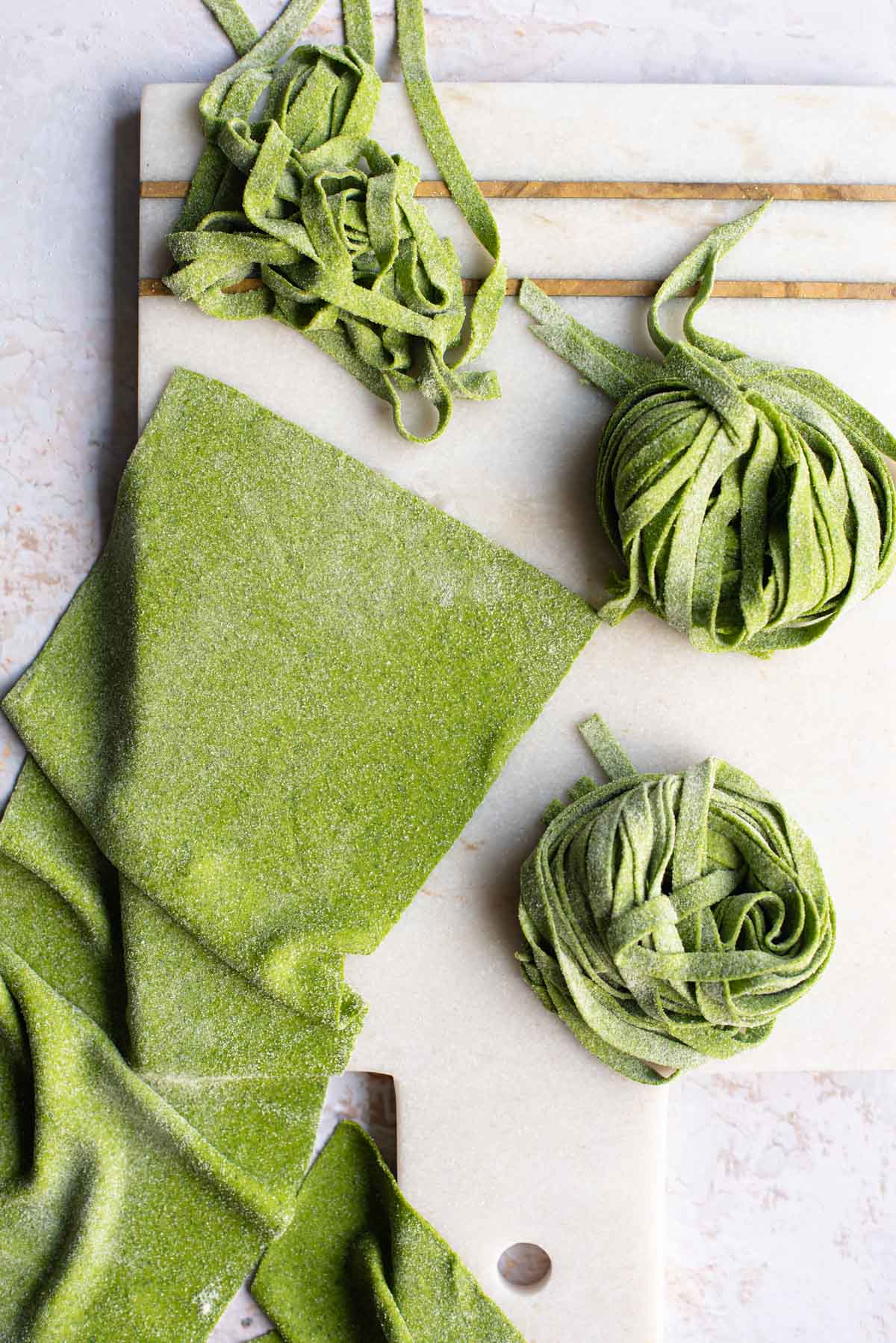 An overhead shot of spinach pasta dough cut into shapes on a light surface