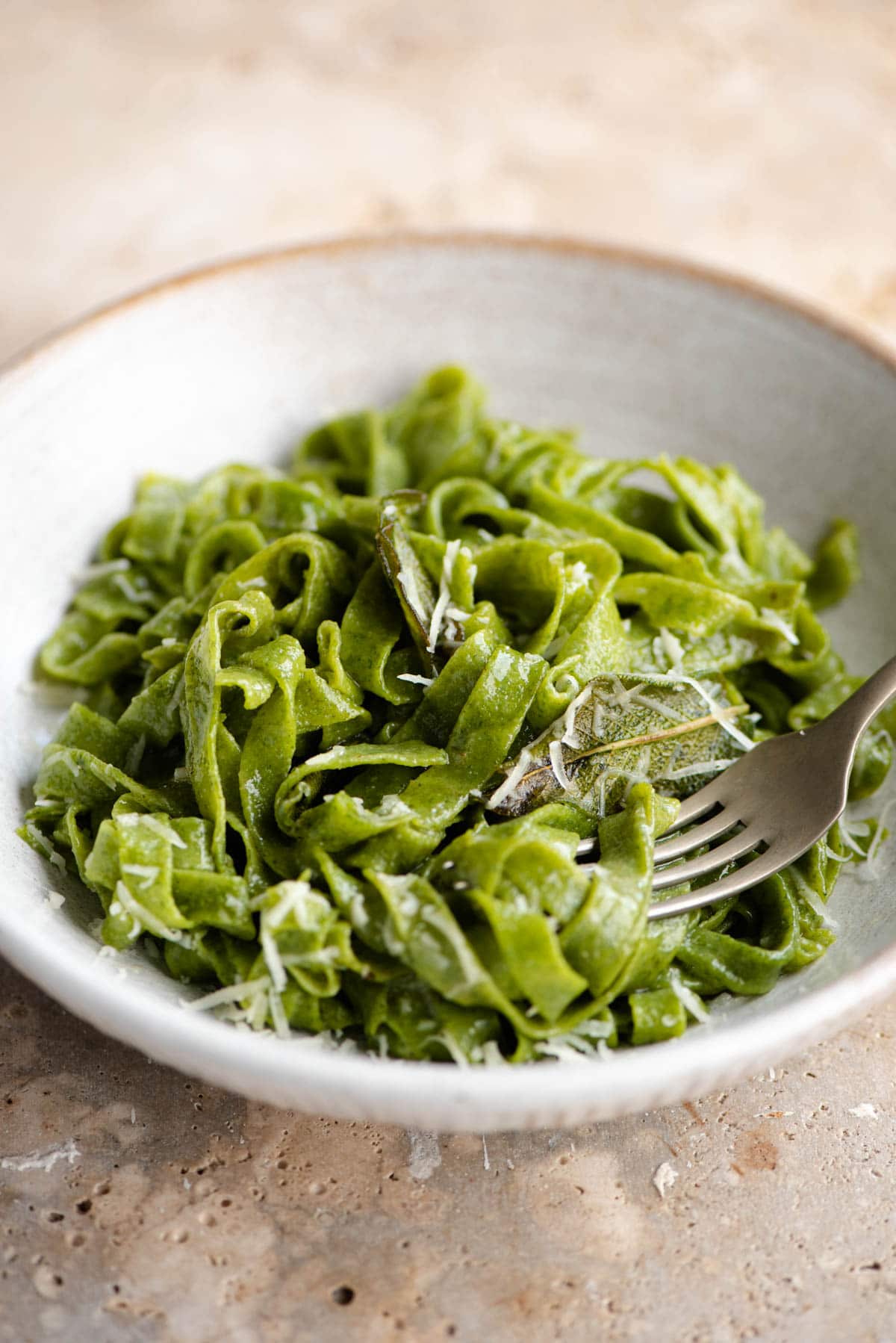 A close up of cooked spinach pasta in a bowl