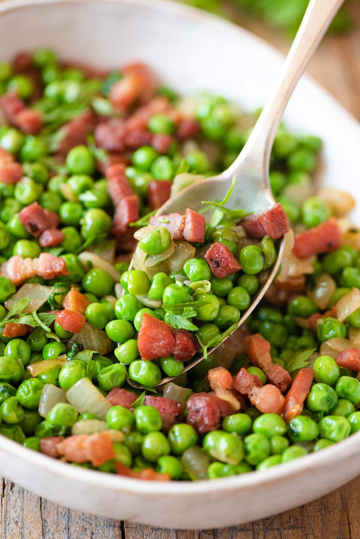 A close up of peas and pancetta on a spoon