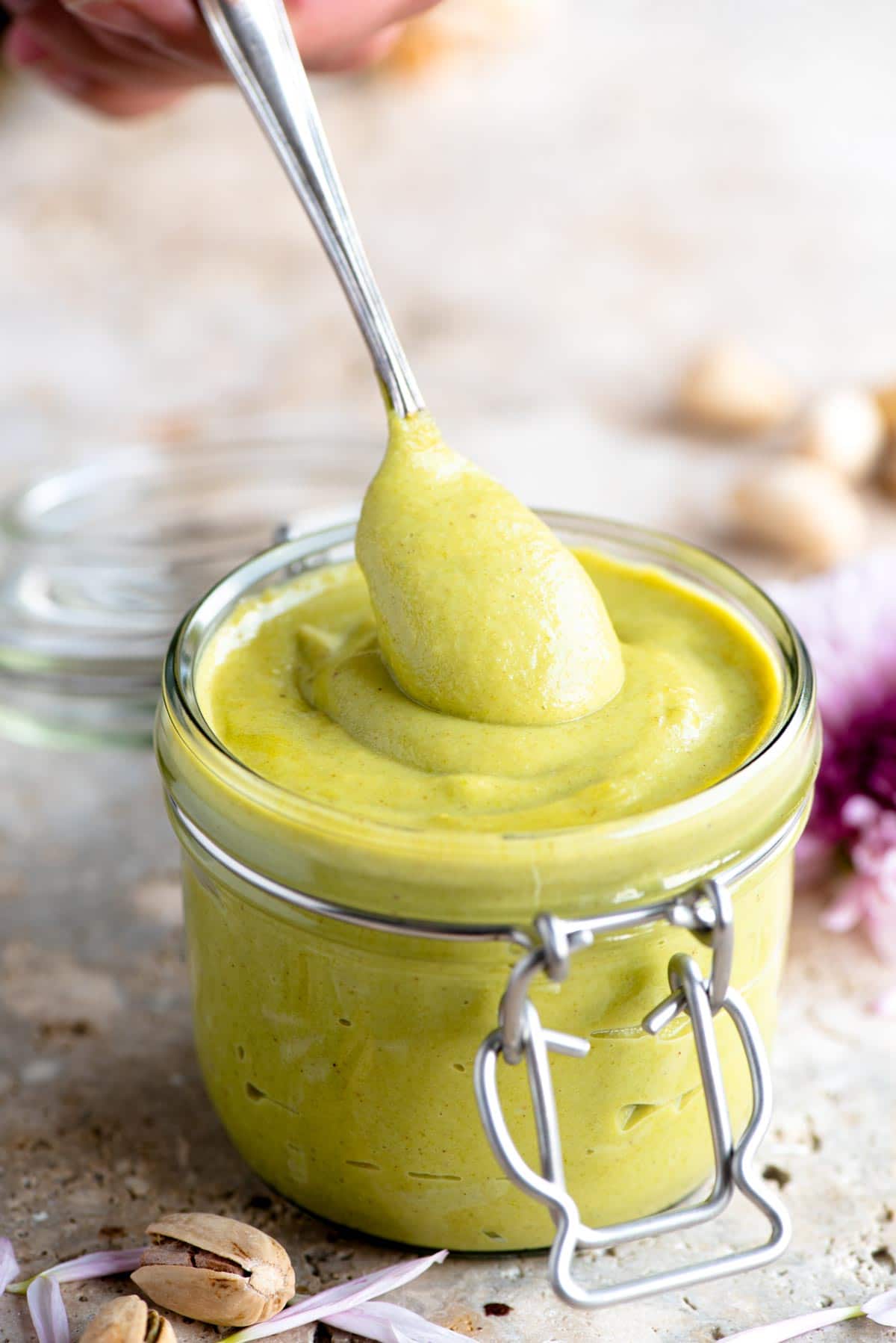A close up of a spoonful of pistachio cream in a jar