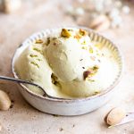 Three scoops of pistachio ice cream in a small bowl with a spoon