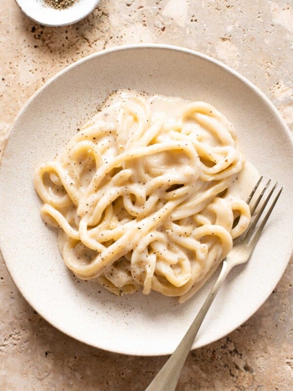 An overhead shot of pici pasta with cacio e pepe sauce on a plate