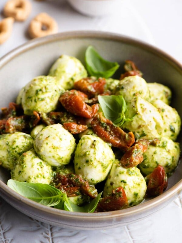 Mozzarella bocconcini in a bowl with basil pesto and tomatoes