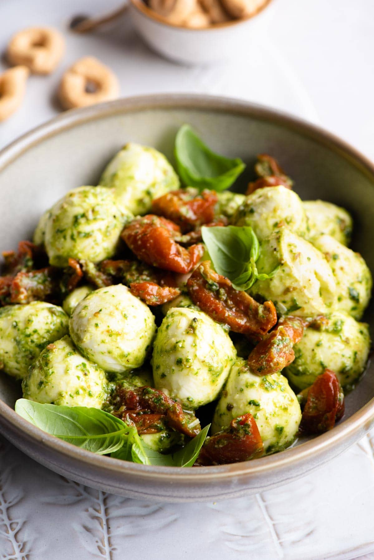 A close up of mozzarella balls mixed with pesto and tomatoes