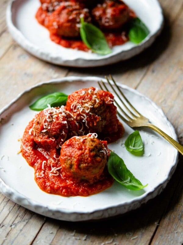 Polpette (Italian meatballs) in a tomato sauce on a plate topped with basil.