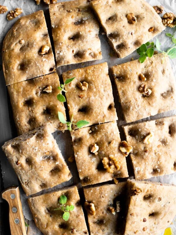 An overhead shot of a walnut focaccia cut into12 squares sprinkled with walnuts