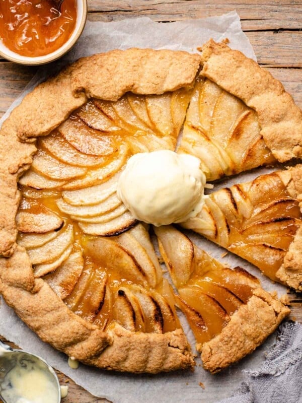 An overhead shot of an apple crostata with some slices cut and a scoop of ice cream on top