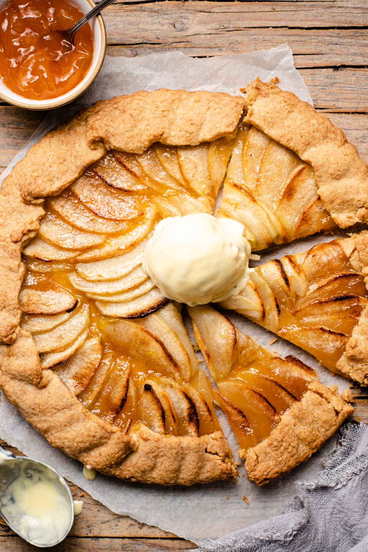 An overhead shot of an apple crostata with some slices cut and a scoop of ice cream on top