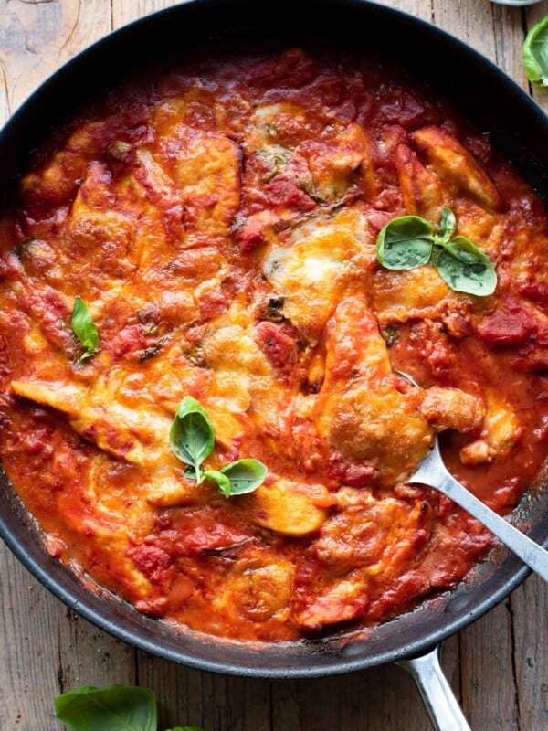 An overhead shot of a skillet with chicken baked in tomato sauce and topped with mozzarella