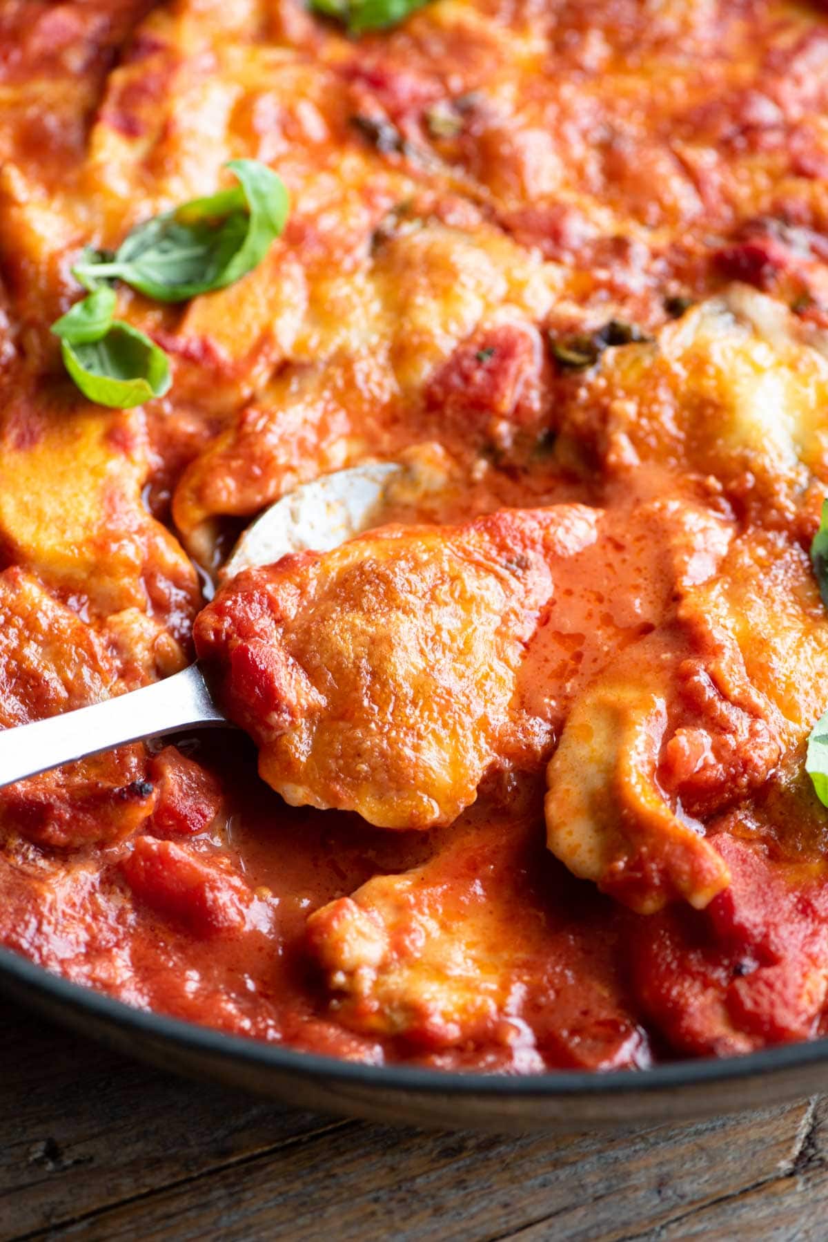 A close up of a piece of chicken sorrentina on a serving spoon