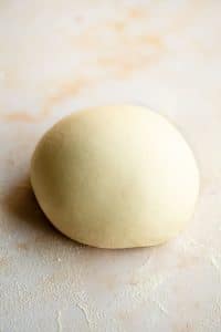 A ball of semolina pasta dough on a light marble surface