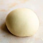 A close up of semolina pasta dough in a ball on a marble surface