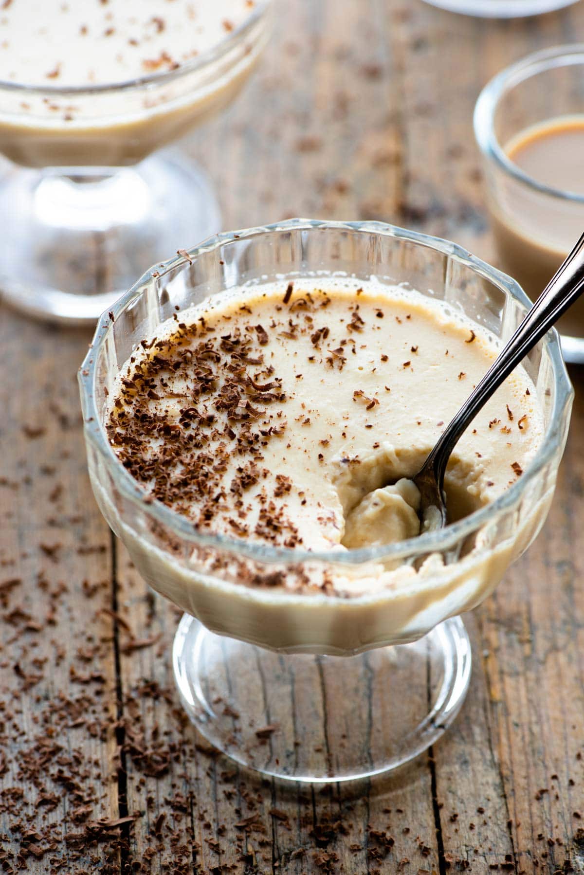 Baileys panna cotta in a small glass dish with a spoon and grated chocolate on top