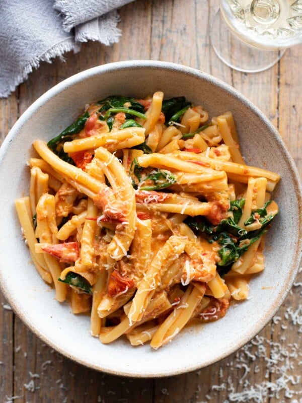 An overhead shot of creamy Nduja pasta in a bowl sitting on a rustic wooden surface