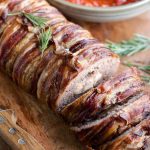 A close up of an Italian meatloaf wrapped in pancetta and stuffed with cheese