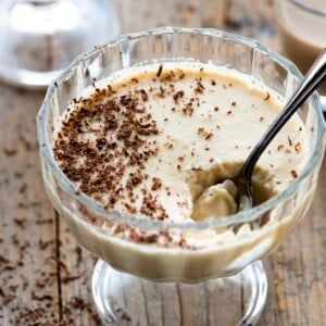 A close up of baileys panna cotta in a small glass bowl with a spoon in it