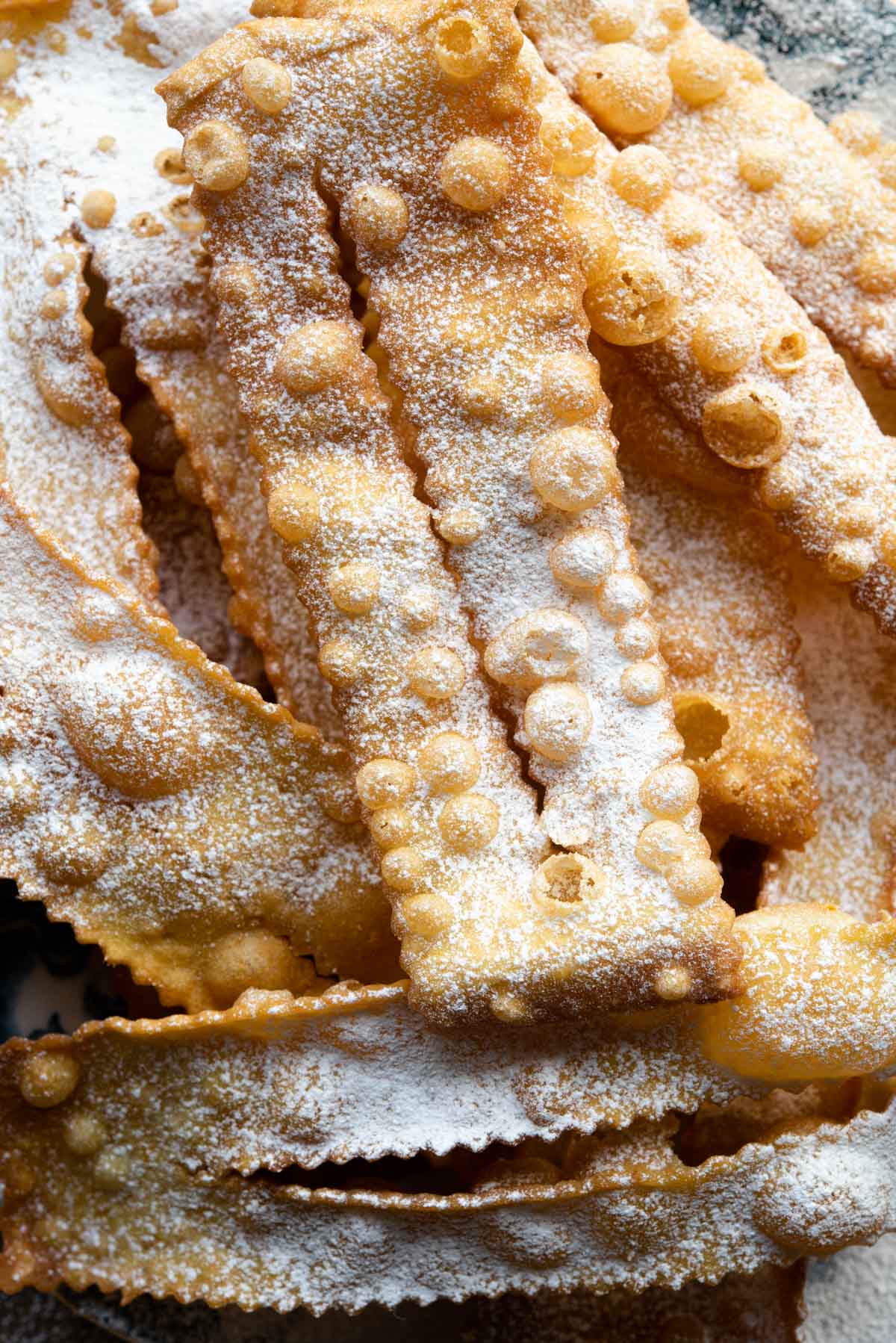 A close up of an Italian fried pastry dusted in powdered sugar