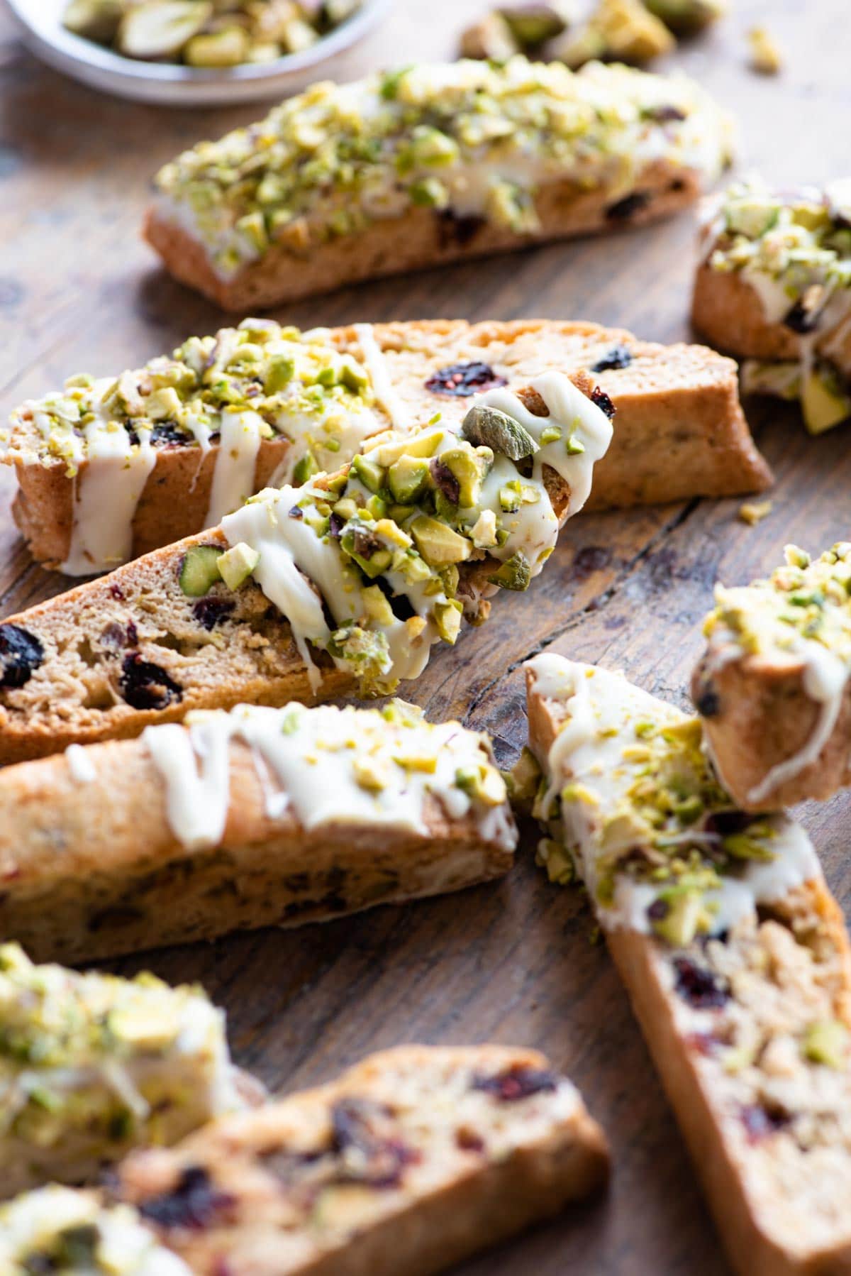 A close up of pistachio biscotti with cranberries and white chocolate on a wooden surface