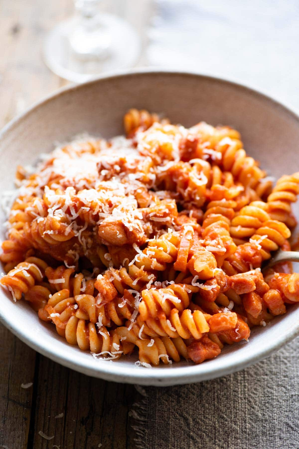 A close up of creamy tomato pasta in a bowl topped with parmesan