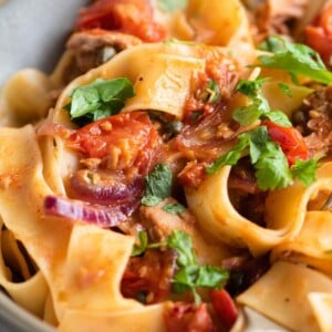 A close up of tuna pasta with tomatoes and parsley