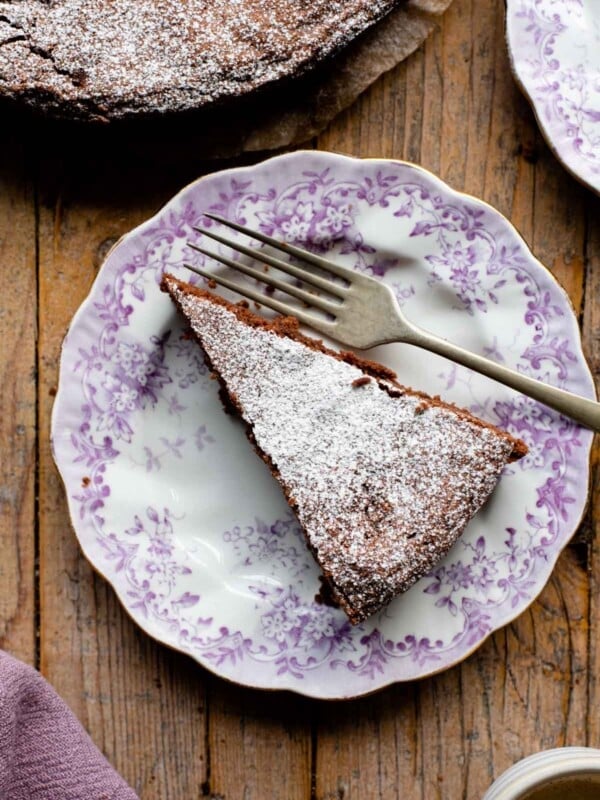 An overhead shot of a slice of chocolate torta caprese on a pink patterned plate
