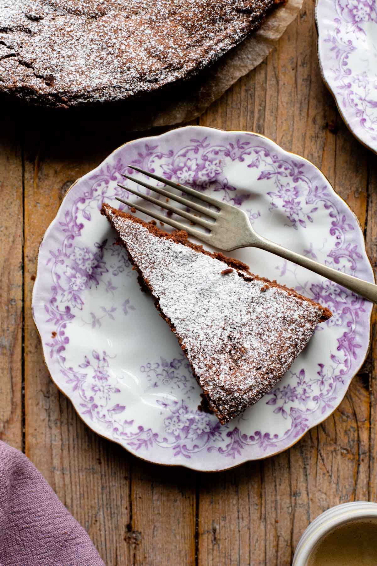 An overhead shot of a slice of chocolate torta caprese on a pink patterned plate