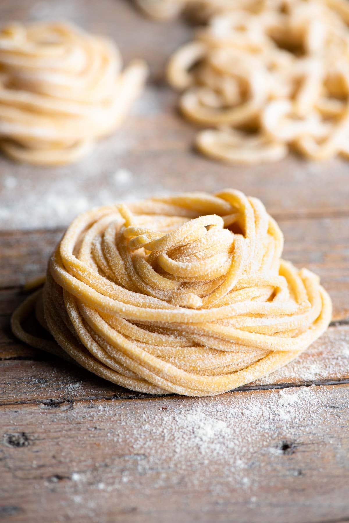 A nest of tonnarelli pasta sitting on a wooden surface