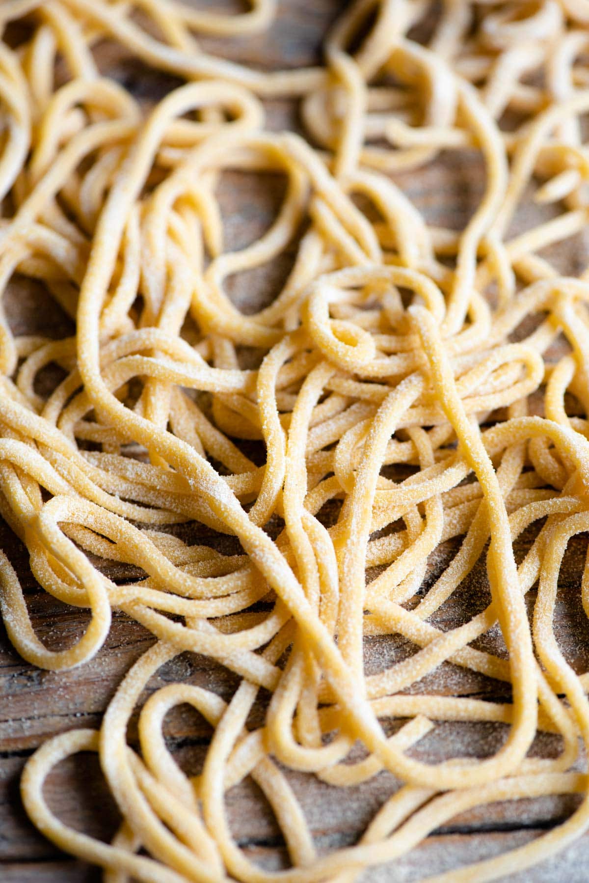 A close up of Tonnarelli pasta aka Spaghetti alla Chitarra scattered on a wooden surface