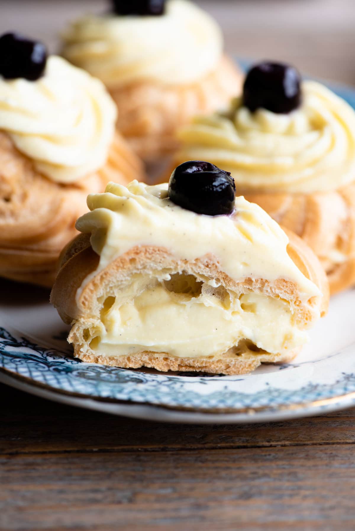 A close up of an Italian pastry cut in half and filled with pastry cream sitting on a blue plate.