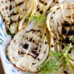 A close up of grilled fennel on a white serving plate