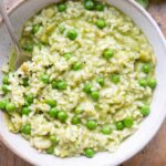 A close up of a bowl of risotto with pesto and peas