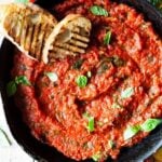 A close up overhead shot of tomato sauce in a skillet with two slices of char-grilled bread at the side.