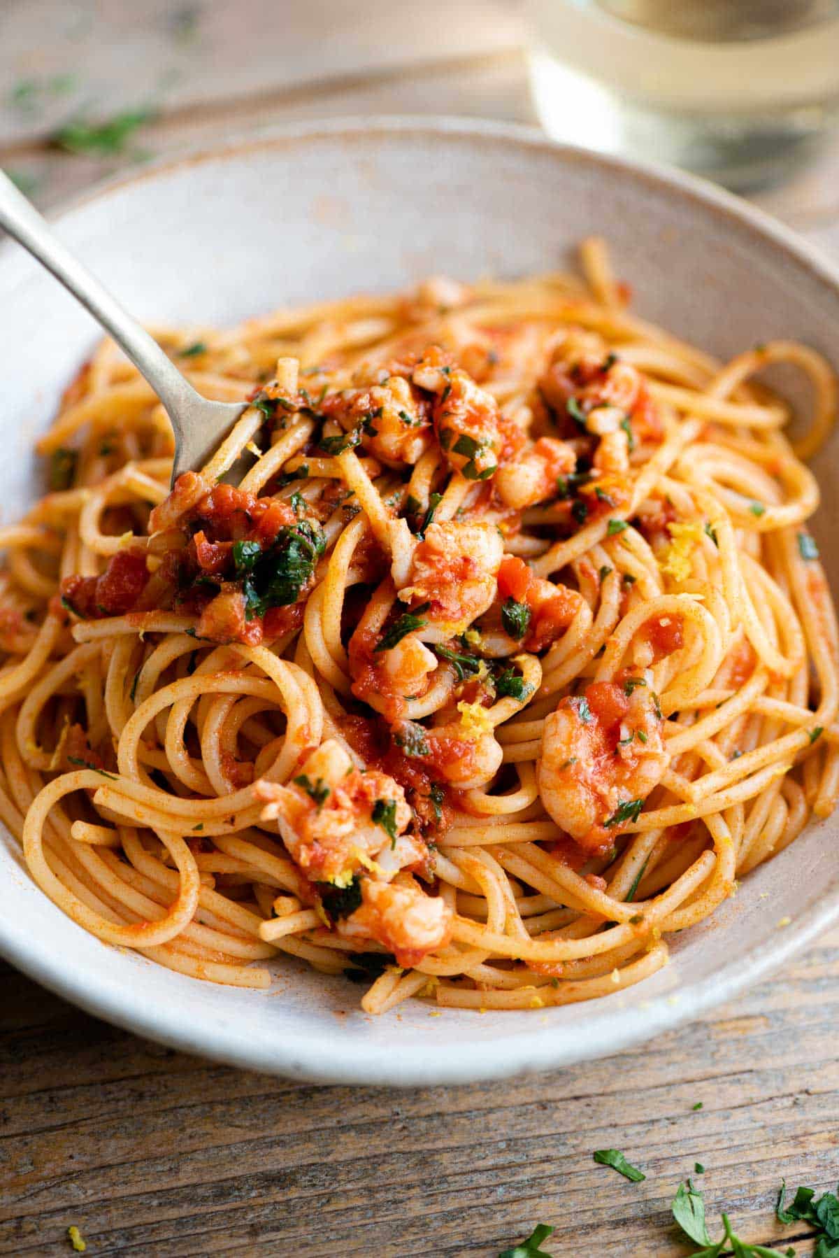 A close up side shot of shrimp spaghetti in a bowl with a fork at the side.