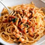 A close up of a fork in a bowl or shrimp spaghetti.